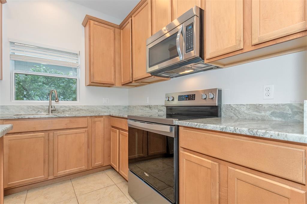 A kitchen features light wood cabinets, stainless steel appliances, and granite countertops — 606 LAKE TALQUIN WAY, GROVELAND, FL
