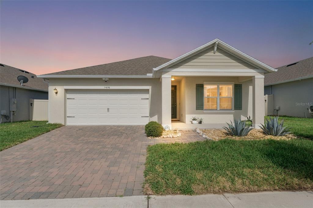 A single-story suburban house with a paved driveway, two-car garage, and a covered front porch — 5476 HUNTER JUMPER LANE, APOPKA, FL