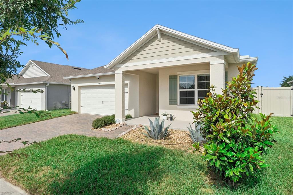 A single-story suburban house with a beige stucco exterior, a garage, and a front porch — 5476 HUNTER JUMPER LANE, APOPKA, FL