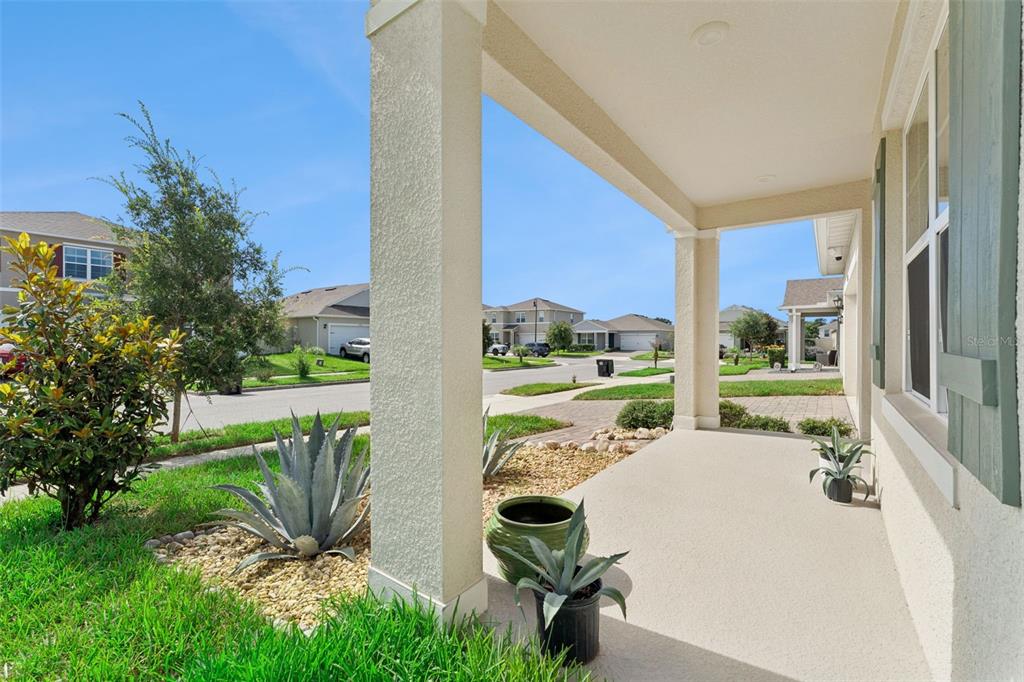 A covered front porch with concrete flooring, support columns, and potted agave plants — 5476 HUNTER JUMPER LANE, APOPKA, FL