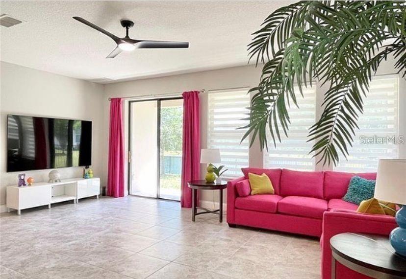 This living room features a slatted wood accent wall, a sectional sofa, and a ceiling fan — 13542 GORGONA ISLE DRIVE, WINDERMERE, FL