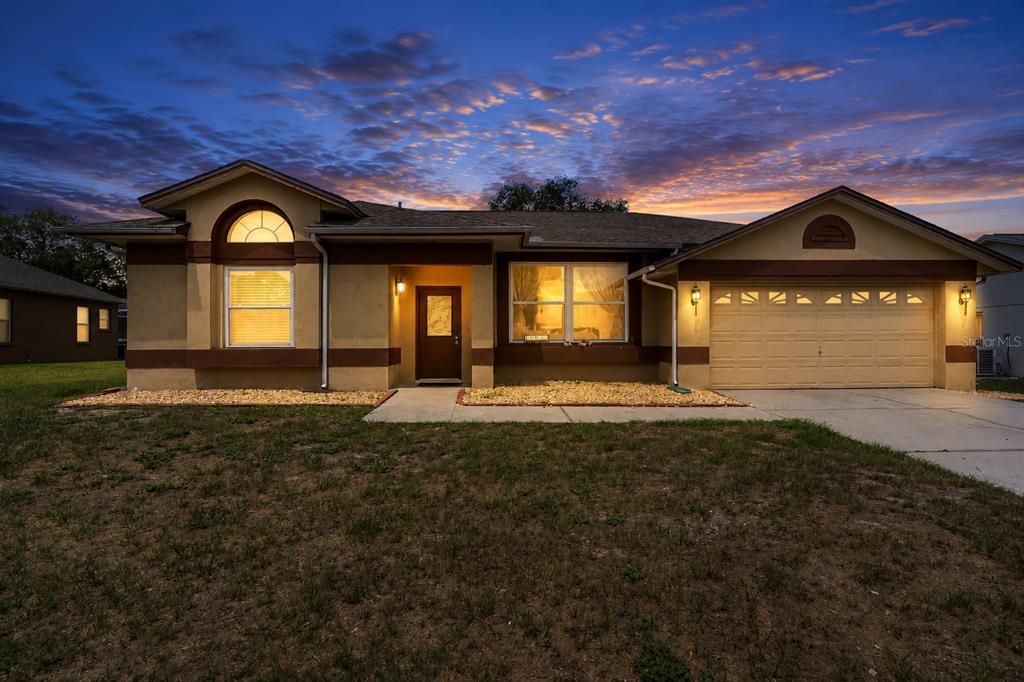 A single-story house with a tan stucco exterior, brown trim, and a two-car garage — 10435 CRESTFIELD DRIVE, RIVERVIEW, FL