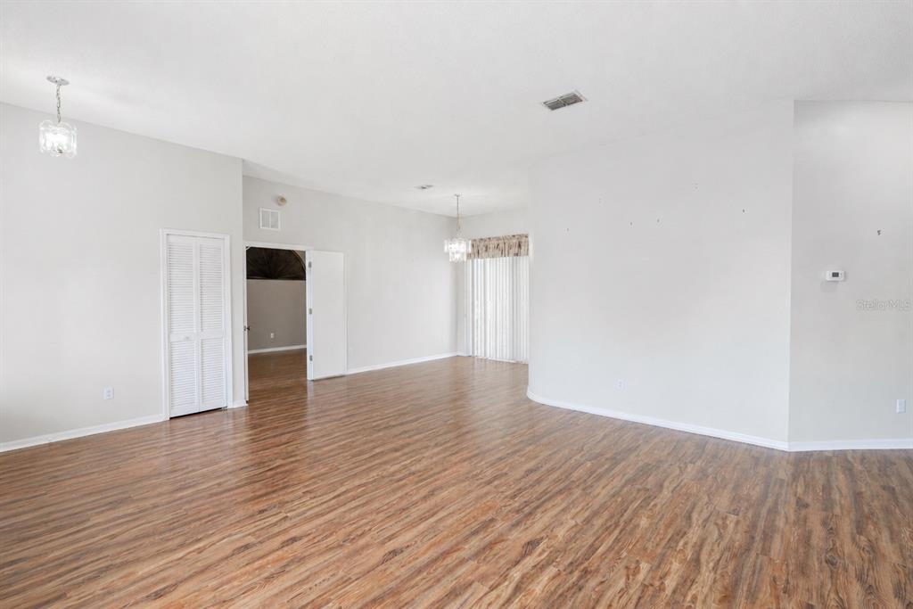 An empty room with wood-look flooring, white walls, a closet, and sliding glass doors — 10435 CRESTFIELD DRIVE, RIVERVIEW, FL