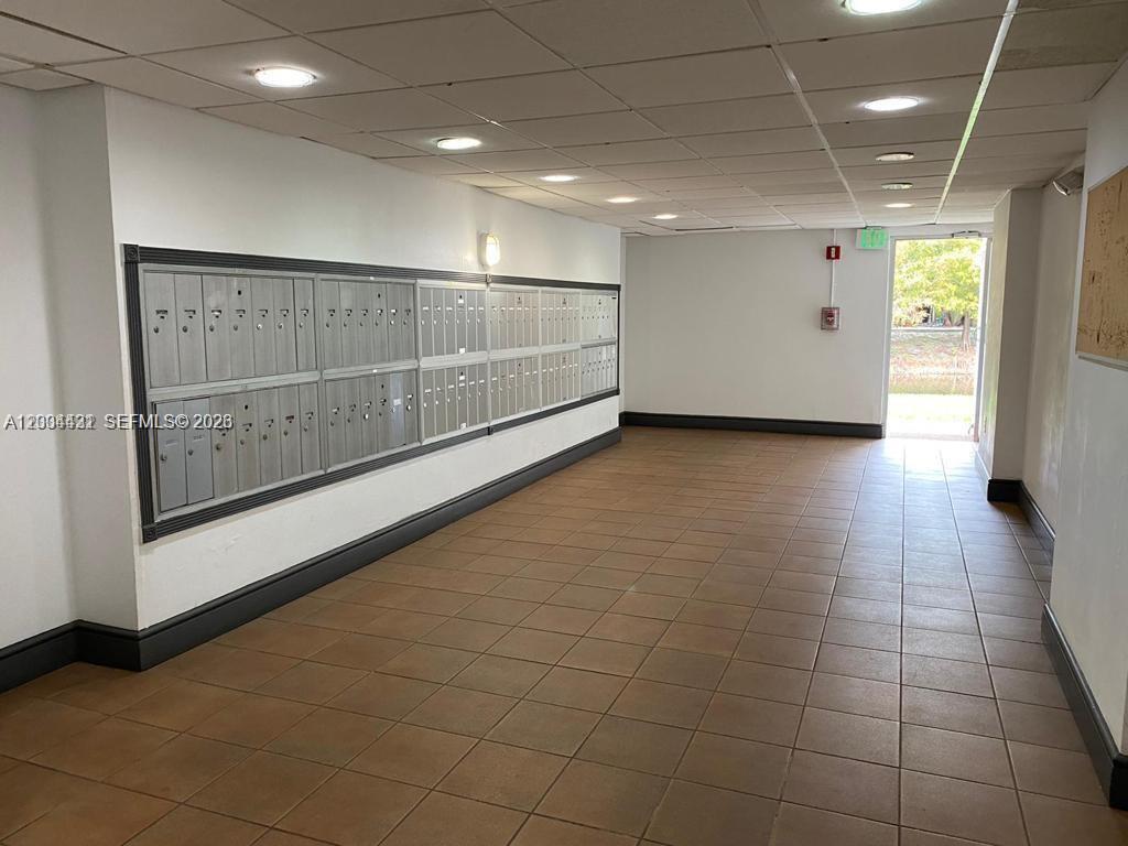 A mailroom features rows of metal mailboxes along a wall with tiled flooring — PLANTATION, FL