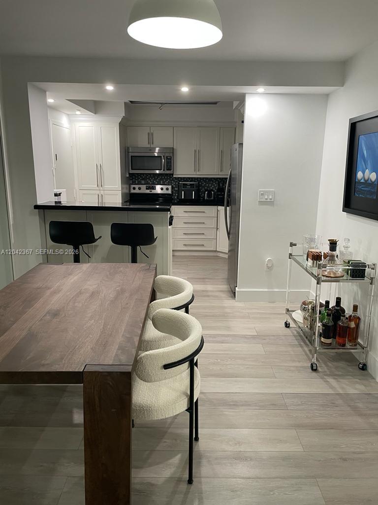 A dining area with a wooden table leads into a kitchen featuring white cabinetry — 2333 Brickell Ave # 314, Miami FL 33129, MIAMI, FL