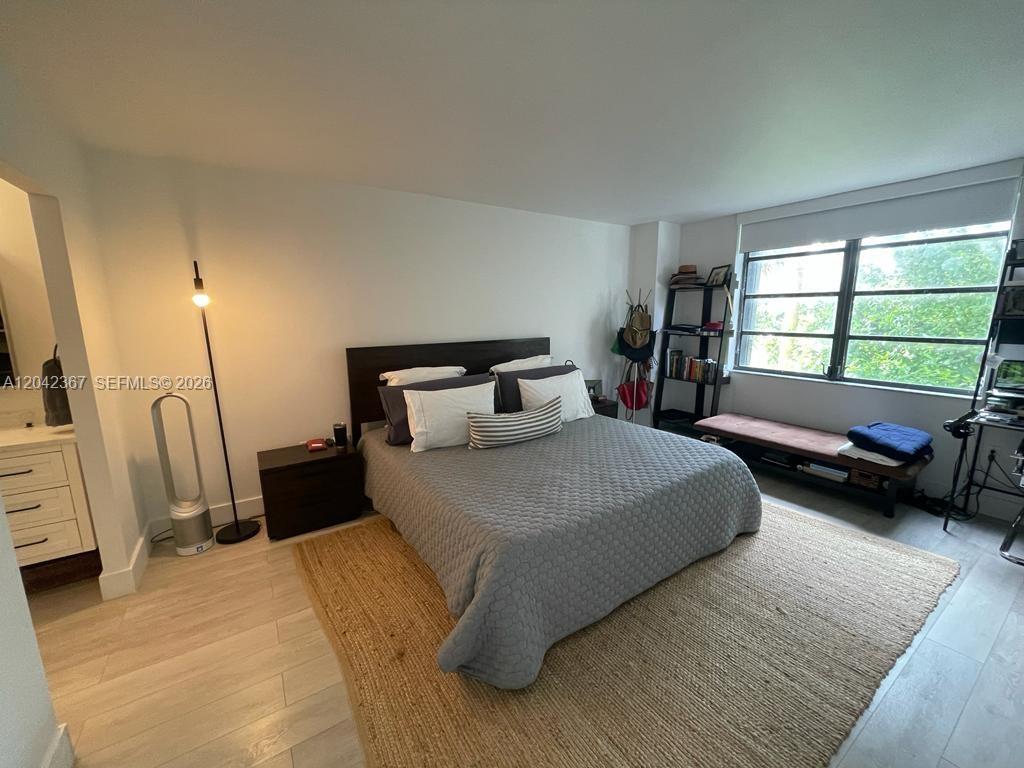 A bedroom features a bed with a gray quilt, a jute rug, and a window — 2333 Brickell Ave # 314, Miami FL 33129, MIAMI, FL