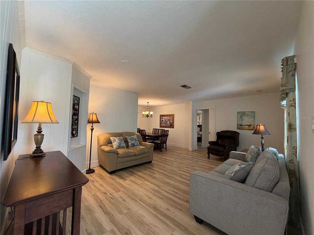 A living room with light wood-look flooring, two sofas, and a dining area in back — 732 SANTA MARGERITA LANE, PUNTA GORDA, FL