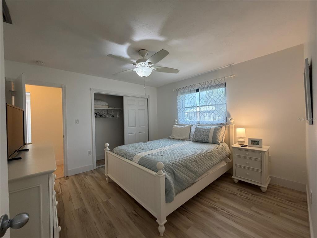 A bedroom features a white bed frame, light wood flooring, a ceiling fan, and a closet — 732 SANTA MARGERITA LANE, PUNTA GORDA, FL