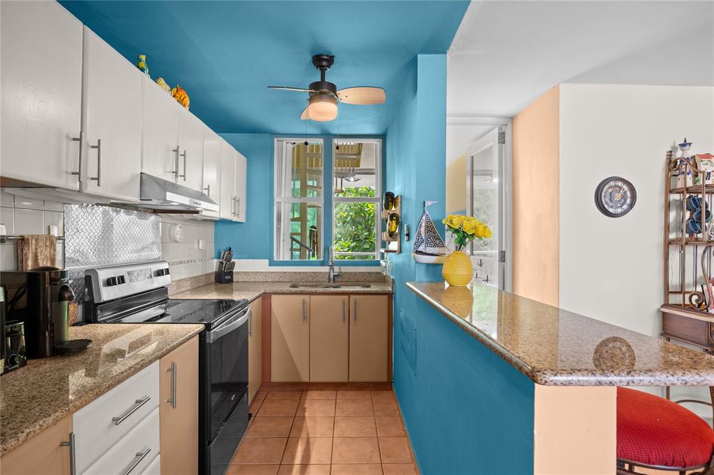 A kitchen with white upper cabinets, tan lower cabinets, granite countertops, and blue painted walls — CII EL CHARLIE UNIT G405, LOIZA, PR
