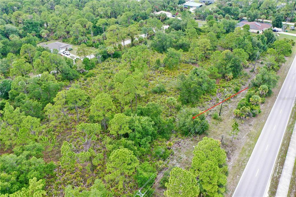 An aerial view of a wooded, undeveloped plot of land adjacent to a paved road — 3129 COLLINGSWOOD BOULEVARD, PORT CHARLOTTE, FL
