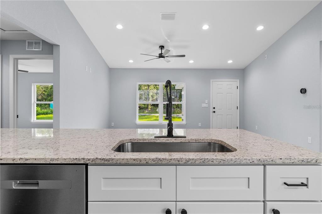 A kitchen island with a stainless steel sink faces a dining area with a ceiling fan — 2512 SW 147TH PLACE ROAD, OCALA, FL