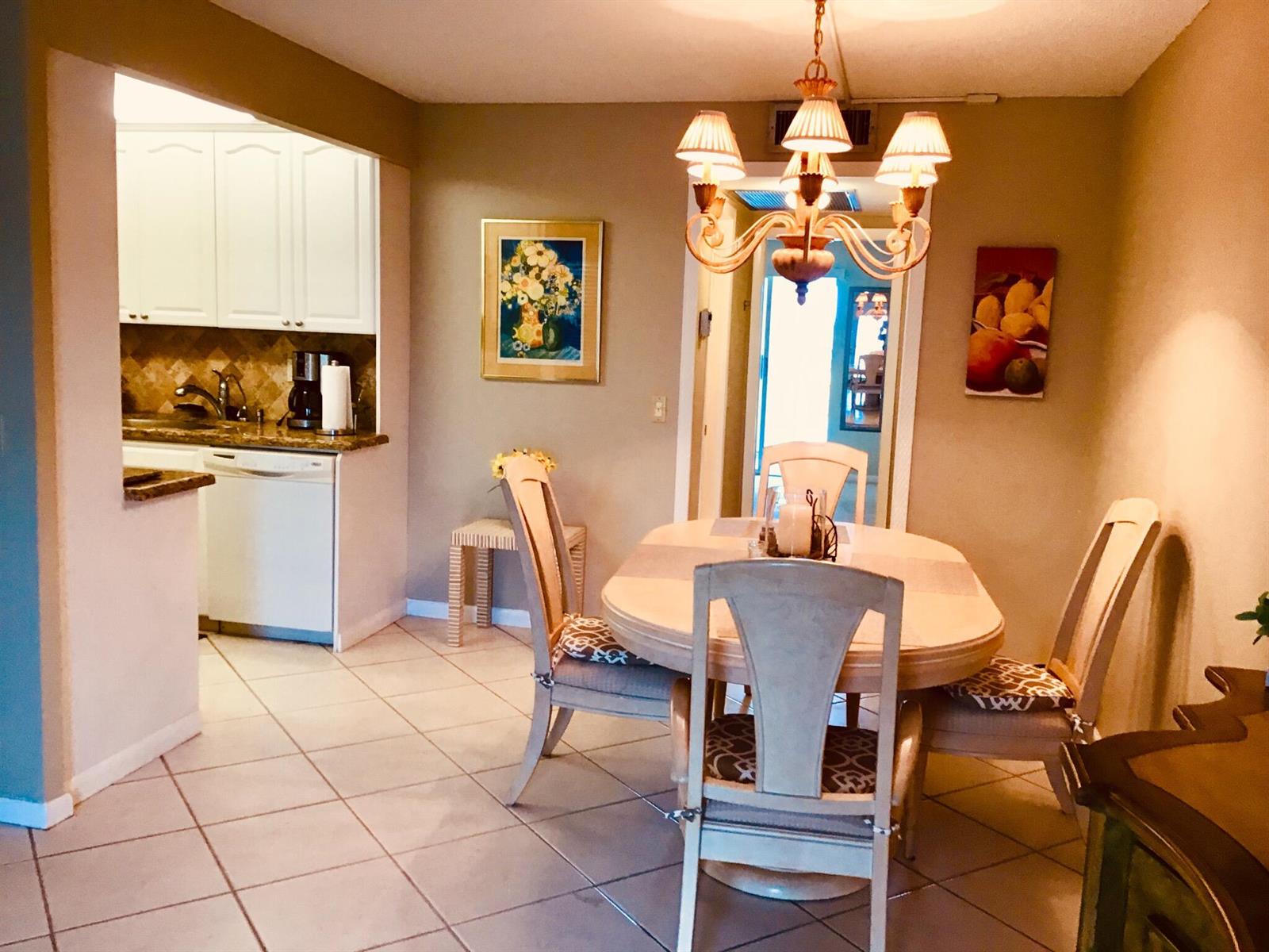 A dining area with a round table, chandelier, and adjacent kitchen with white cabinets — 4008 Cornwall A, Boca Raton FL 33434, BOCA RATON, FL