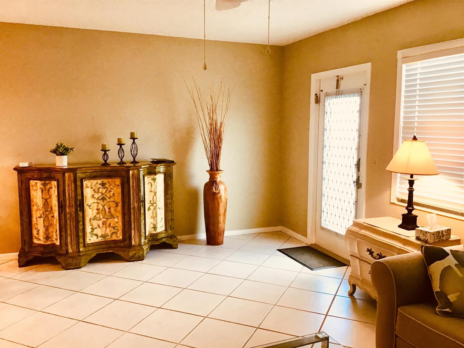 An entryway features tile flooring, a decorative wooden cabinet, a tall floor vase, and door — 4008 Cornwall A, Boca Raton FL 33434, BOCA RATON, FL