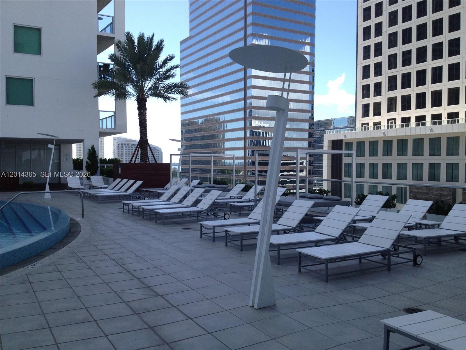 A rooftop pool deck features rows of white lounge chairs and modern light fixtures — 55 SE 6th St # 2106, Miami FL 33131, MIAMI, FL
