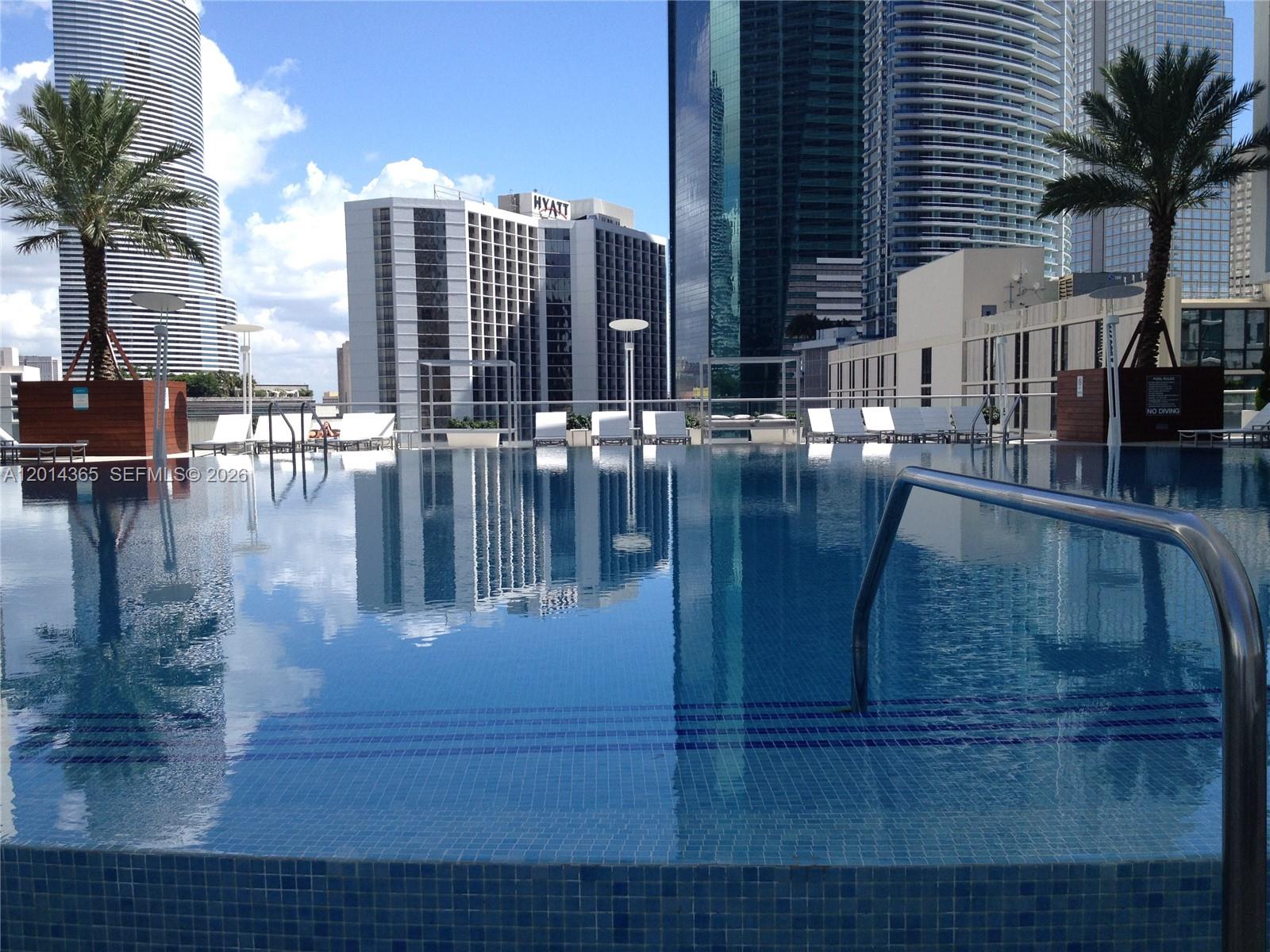A swimming pool overlooks a city skyline with tall buildings and palm trees — 55 SE 6th St # 2106, Miami FL 33131, MIAMI, FL