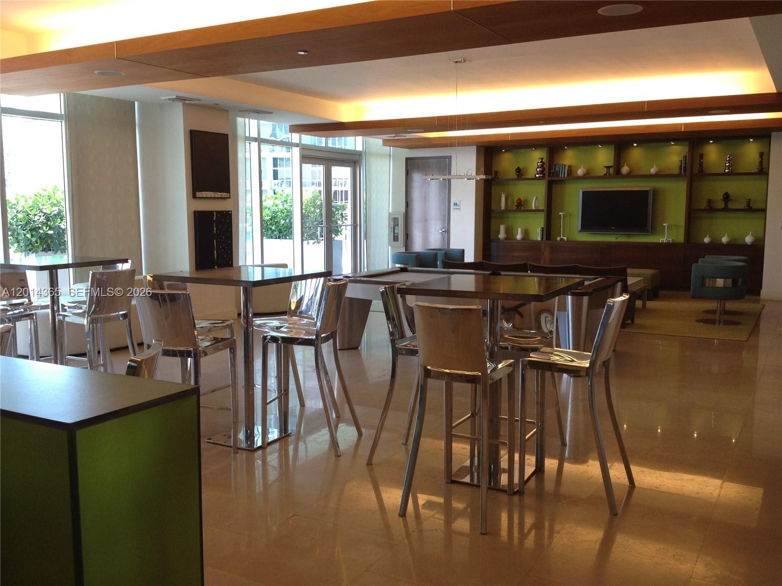 A modern lounge area features high-top tables, metal chairs, a pool table, and built-in shelving — 55 SE 6th St # 2106, Miami FL 33131, MIAMI, FL