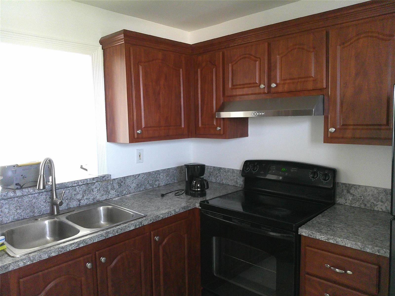 A kitchen features wood cabinets, gray laminate countertops, a stainless steel sink, and black appliances — 403 NW 68th Avenue # 519, Plantation FL 33317, PLANTATION, FL