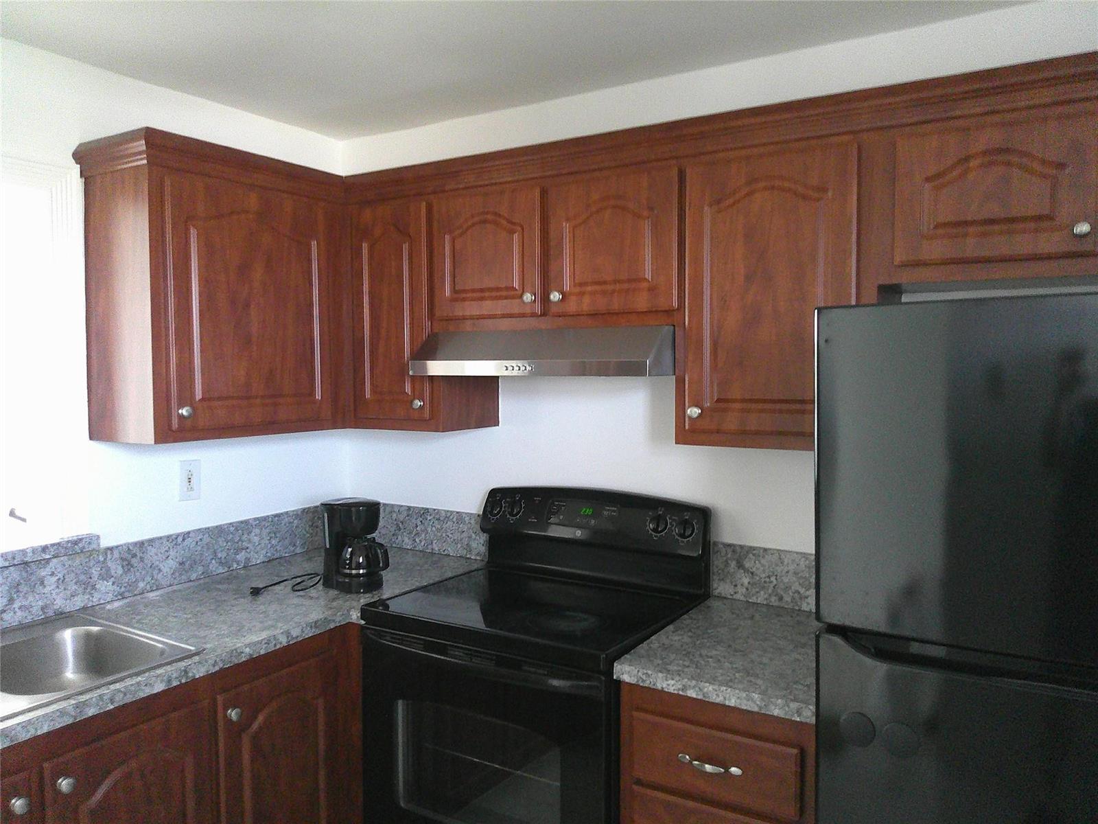 A kitchen features wood cabinets, gray countertops, a black stove, and a black refrigerator — 403 NW 68th Avenue # 519, Plantation FL 33317, PLANTATION, FL