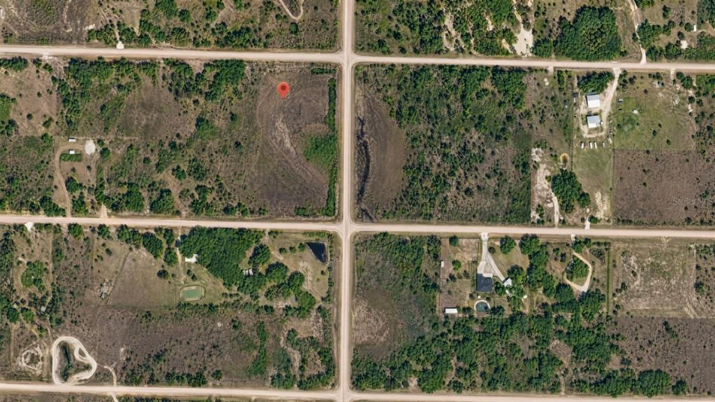 An aerial view of a vacant, wooded lot marked with a red pin — 16062 NW 310TH STREET, OKEECHOBEE, FL