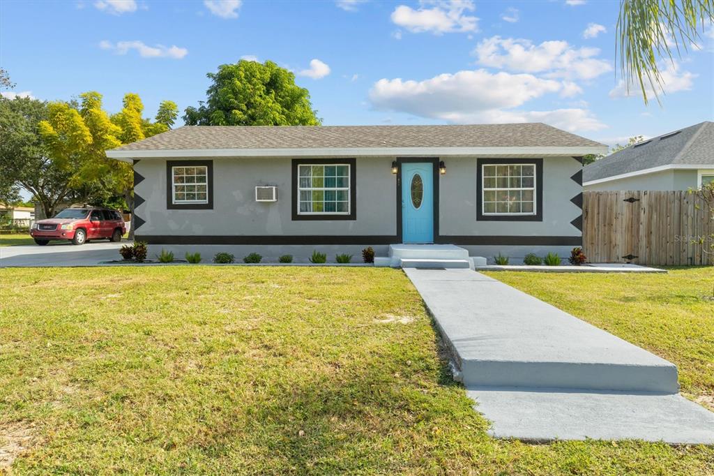 A single-story gray house with a light blue front door and a concrete walkway — 513 5TH STREET, DUNDEE, FL