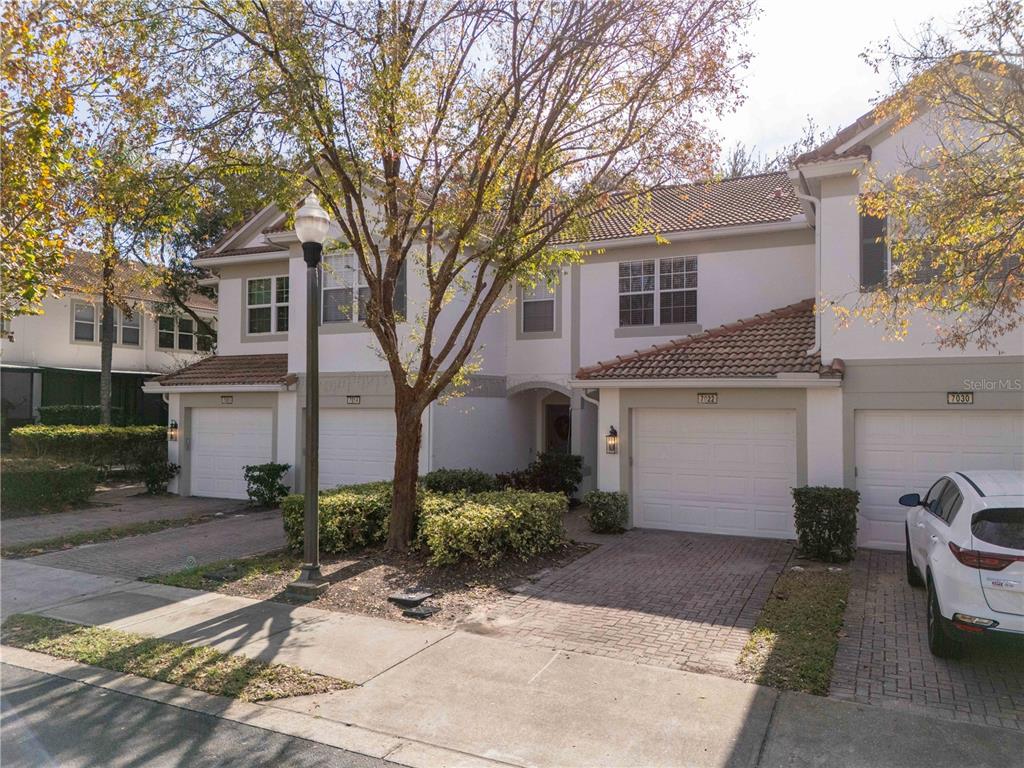 An exterior view of a multi-unit townhouse complex with brick driveways and attached garages — 6979 SPERONE STREET, ORLANDO, FL