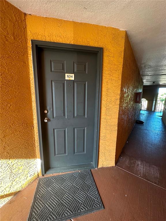 A dark gray apartment door with the number 834 sits in a bright orange hallway — 4658 COMMANDER DRIVE UNIT 834, ORLANDO, FL