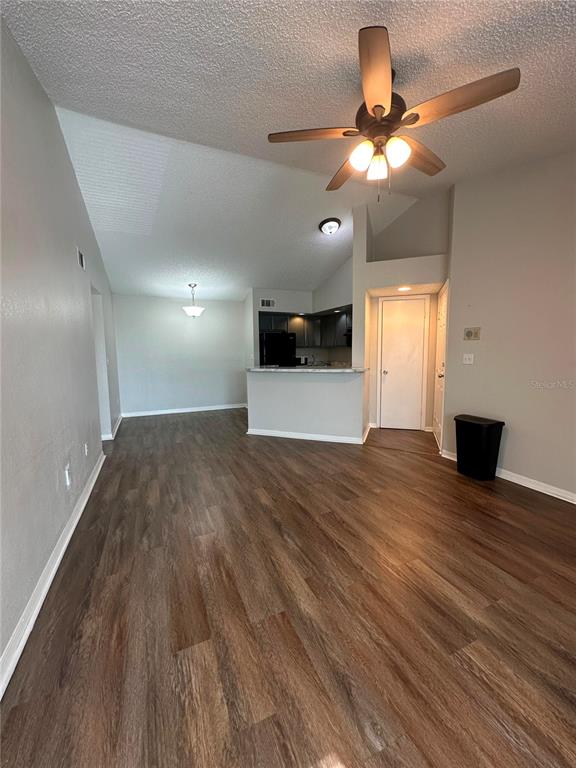 An open-concept living area features wood-look flooring, a ceiling fan, and a kitchen pass-through — 4658 COMMANDER DRIVE UNIT 834, ORLANDO, FL