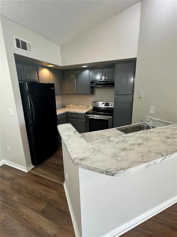 A kitchen features dark gray cabinets, black appliances, and a white marble-patterned laminate countertop — 4658 COMMANDER DRIVE UNIT 834, ORLANDO, FL