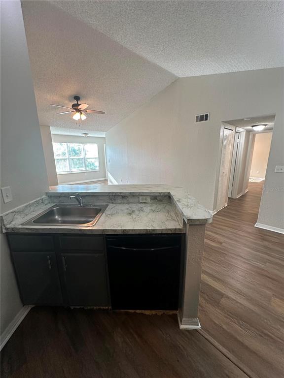 A kitchen sink and dishwasher are set into a countertop with a view toward a hallway — 4658 COMMANDER DRIVE UNIT 834, ORLANDO, FL