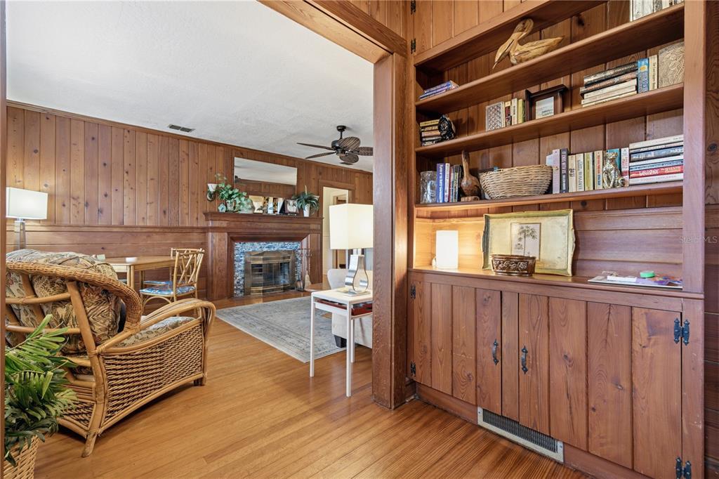 A living room with wood-paneled walls, a fireplace, and built-in bookshelves — 411 W 48TH STREET, BRADENTON, FL
