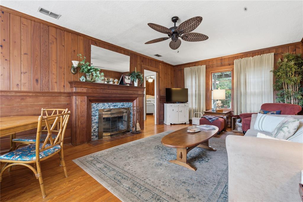 A living room features wood-paneled walls, a fireplace with blue tile, and a ceiling fan — 411 W 48TH STREET, BRADENTON, FL