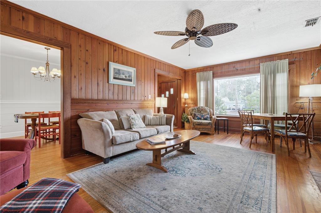 A living room features wood-paneled walls, a beige sofa, a coffee table, and a ceiling fan — 411 W 48TH STREET, BRADENTON, FL