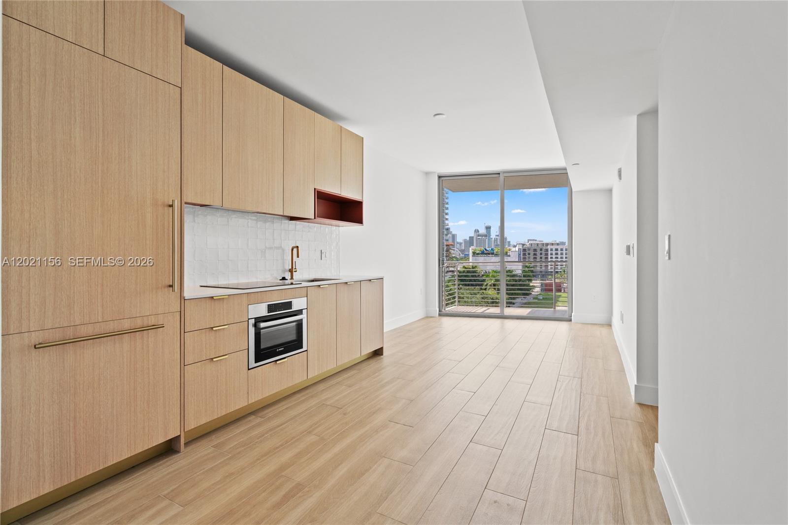 A modern kitchen with light wood cabinetry and a balcony overlooking a city skyline — 90 NE 32nd St # 627, Miami FL 33137, MIAMI, FL