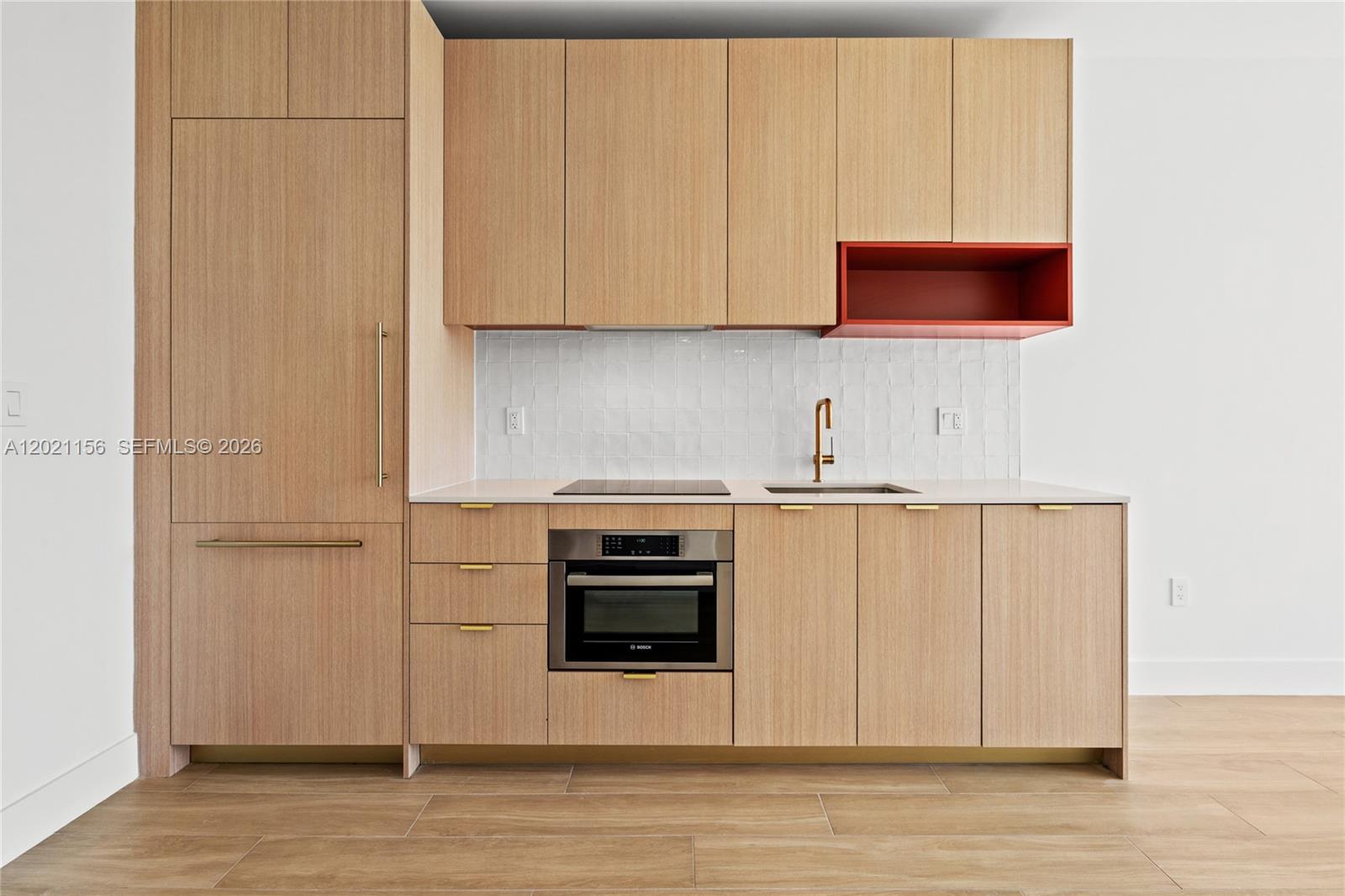 A modern kitchen features light wood cabinetry, a red open shelf, and a white backsplash — 90 NE 32nd St # 627, Miami FL 33137, MIAMI, FL