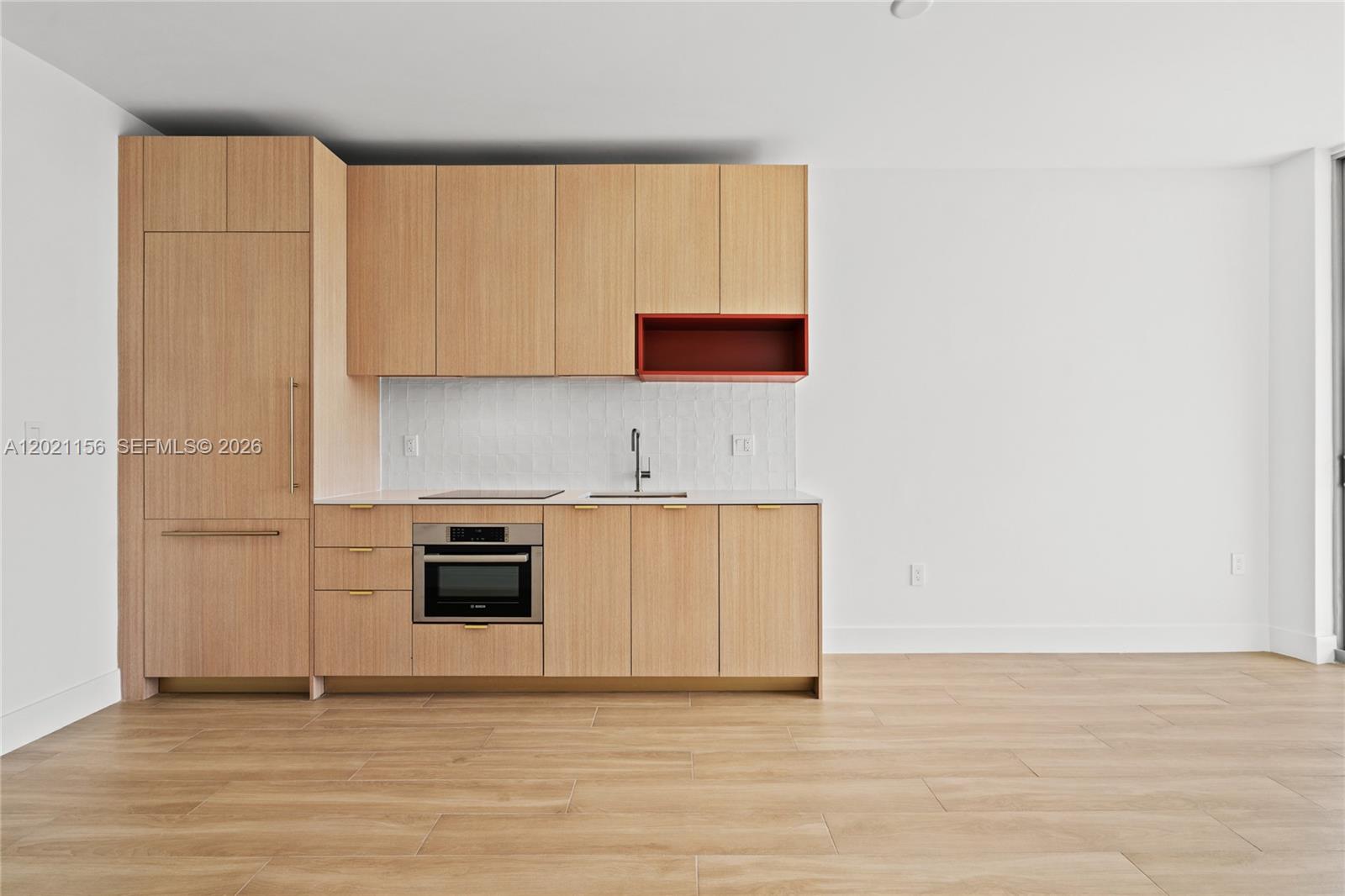 A modern kitchen features light wood cabinetry, a red open shelf, and white tiled backsplash — 90 NE 32nd St # 627, Miami FL 33137, MIAMI, FL
