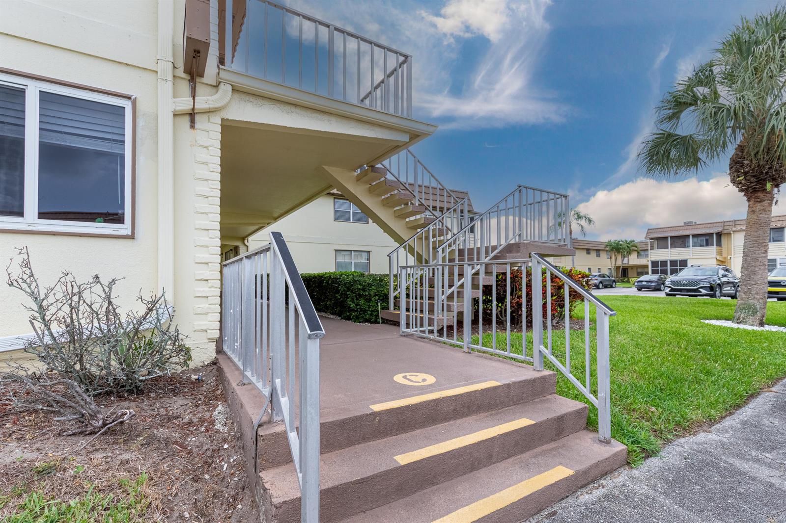 Exterior view of a multi-story apartment building with concrete stairs and metal railings — 141 Saxony C Terrace # 141, Delray Beach FL 33446, DELRAY BEACH, FL