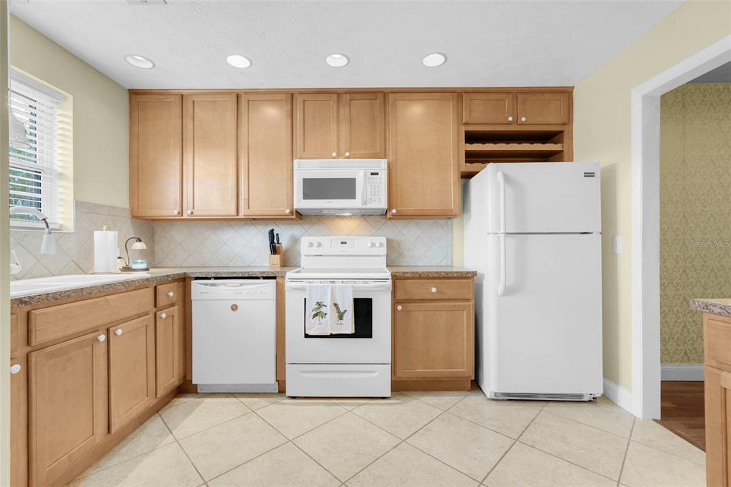 A kitchen features light wood cabinets, white appliances, a tiled backsplash, and diagonal floor tiles — 4224 LAKE UNDERHILL ROAD UNIT 8B8, ORLANDO, FL
