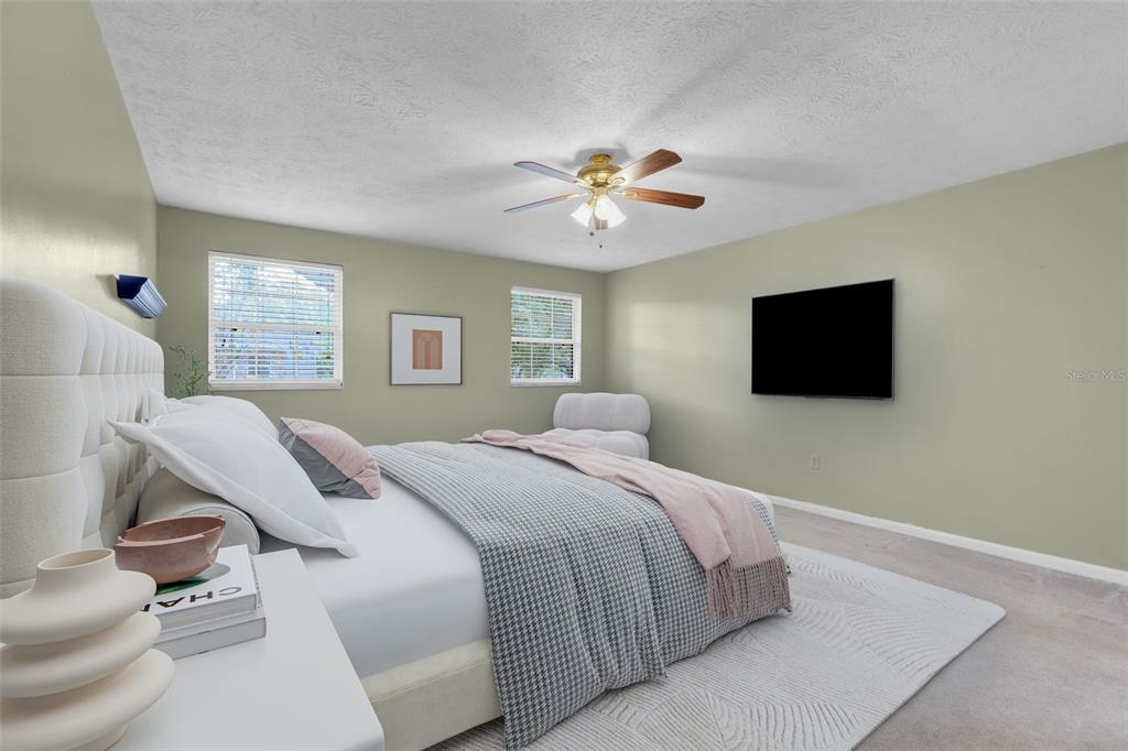 A bedroom features a tufted headboard, a wall-mounted television, and a ceiling fan — 4224 LAKE UNDERHILL ROAD UNIT 8B8, ORLANDO, FL