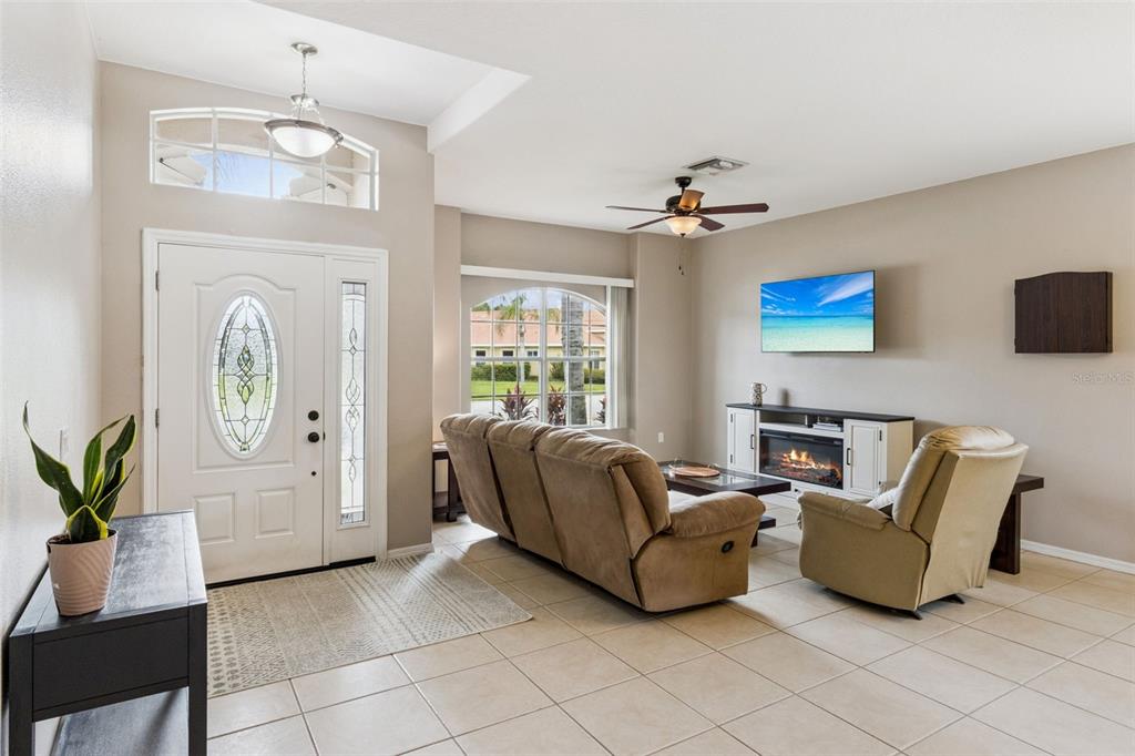A living room features tile floors, a fireplace console, a ceiling fan, and an entryway door — 1742 ALTAVISTA CIRCLE CIRCLE, LAKELAND, FL