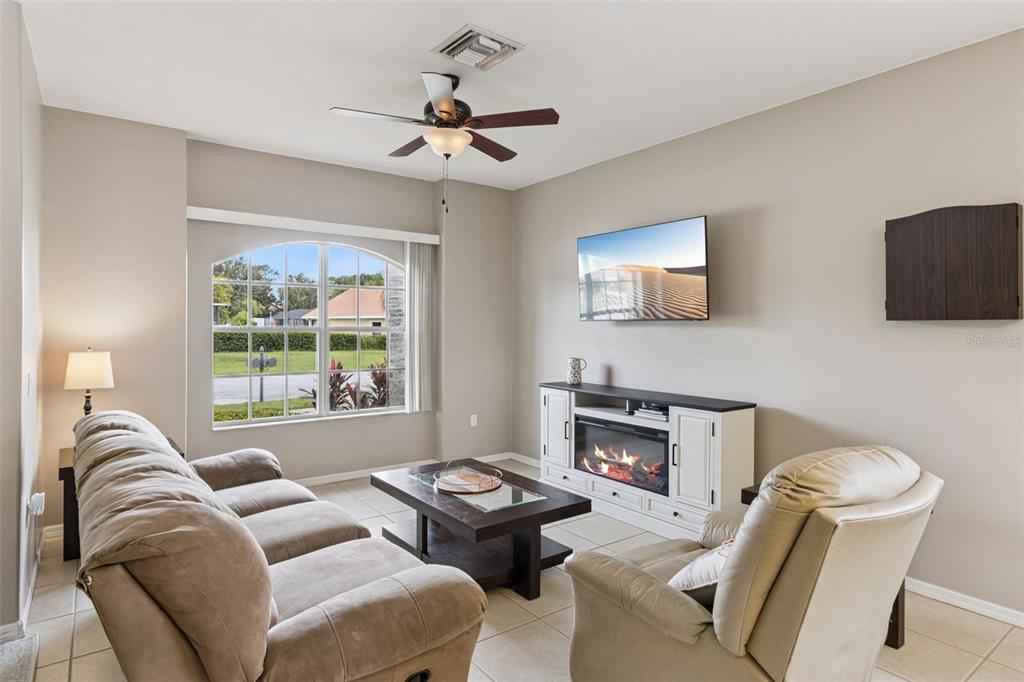 A living room features a sofa, recliner, coffee table, fireplace console, and a wall-mounted television — 1742 ALTAVISTA CIRCLE CIRCLE, LAKELAND, FL