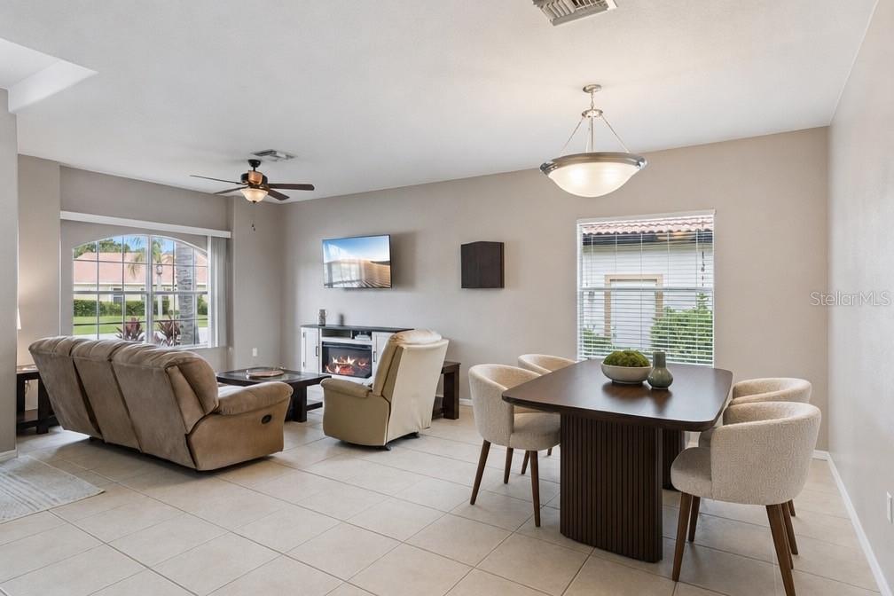 An open-concept living and dining area features tile flooring, a fireplace, and neutral walls — 1742 ALTAVISTA CIRCLE CIRCLE, LAKELAND, FL