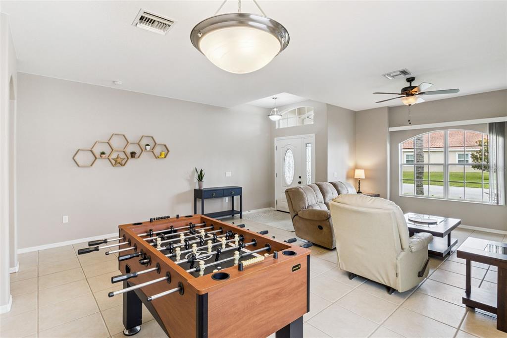 A living room features a foosball table, beige tile flooring, and a ceiling fan — 1742 ALTAVISTA CIRCLE CIRCLE, LAKELAND, FL