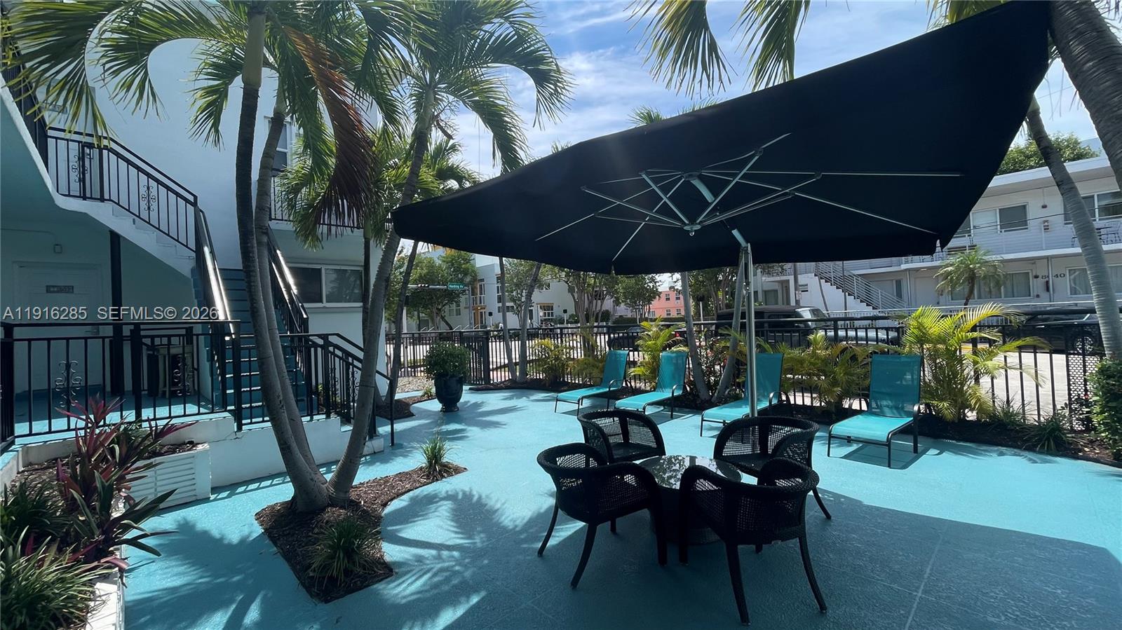 An outdoor patio area features a black umbrella, patio furniture, and lounge chairs — 8100 Harding Ave # 508, Miami Beach FL 33141, MIAMI BEACH, FL