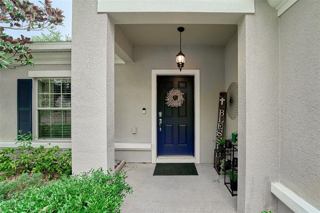 A covered entryway features a dark blue front door with a wreath and a porch light — 2802 WINGLEWOOD CIRCLE, LUTZ, FL