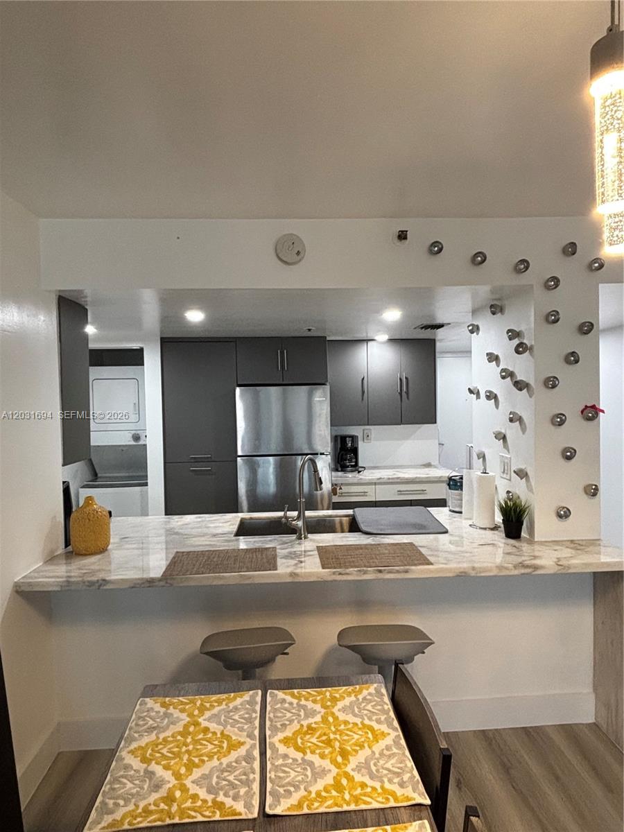 A kitchen features gray cabinets, stainless steel appliances, and a marble-topped breakfast bar with stools — 1717 N Bayshore Dr # 1652, Miami FL 33132, MIAMI, FL