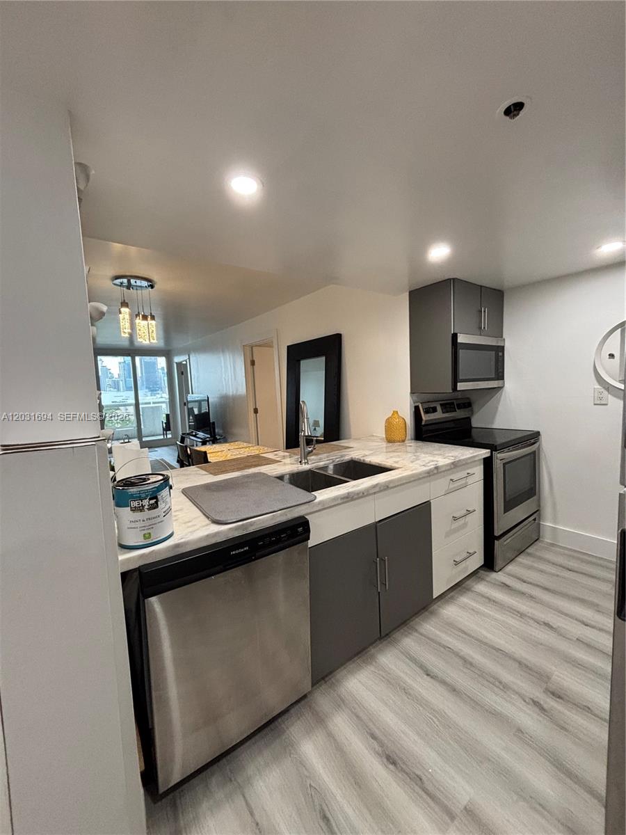 A kitchen features gray and white cabinetry, stainless steel appliances, and light-colored countertops — 1717 N Bayshore Dr # 1652, Miami FL 33132, MIAMI, FL