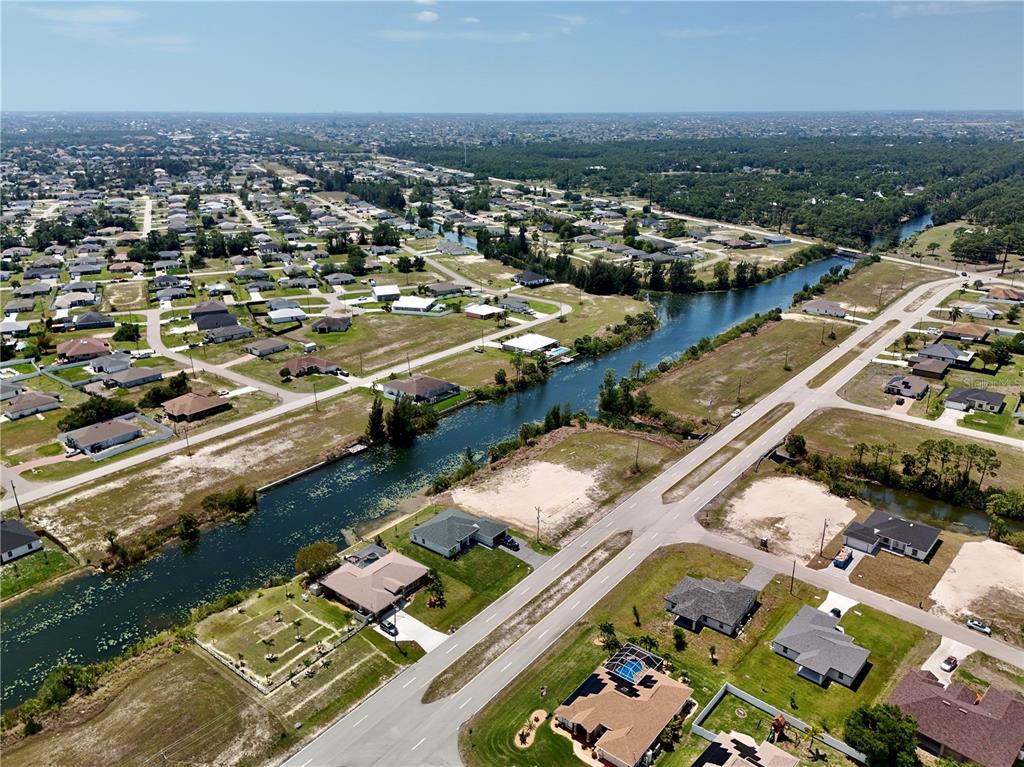 An aerial view shows a suburban neighborhood with houses, a canal, and paved roads — 900 VOGIANTZIS PARKWAY, CAPE CORAL, FL