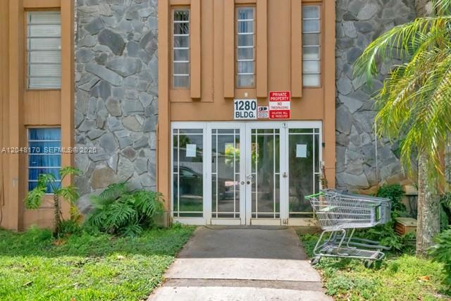 A shopping cart sits on a concrete path in front of a stone-faced building entrance — 1280 W 54th St # 313B, Hialeah FL 33012, HIALEAH, FL