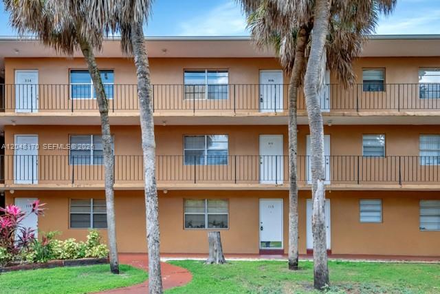 A three-story apartment building with tan stucco walls, black railings, and palm trees in front — 1280 W 54th St # 313B, Hialeah FL 33012, HIALEAH, FL