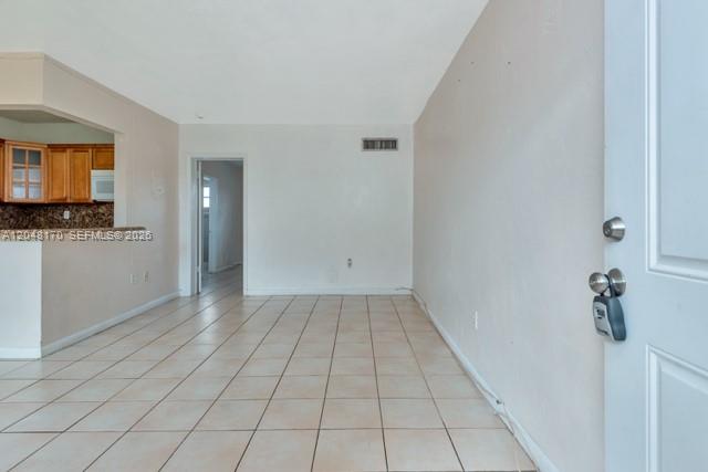 An interior view shows a tiled room with a kitchen area and an open doorway — 1280 W 54th St # 313B, Hialeah FL 33012, HIALEAH, FL